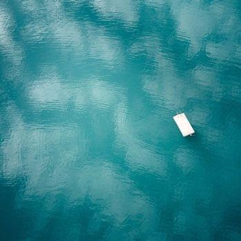 Kärntner Seen Schwimmender Holzsteg auf ruhigem türkisfarbenem See mit Himmelsreflexionen